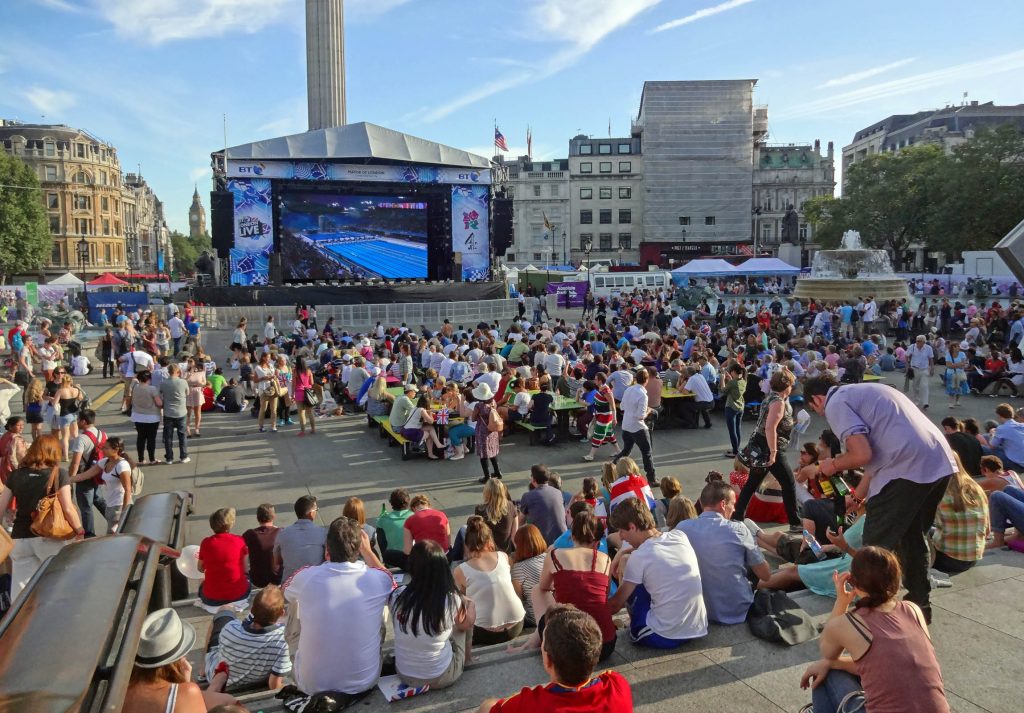 People in Trafalgar Square, watching a London 2012 swimming event on a sunny evening