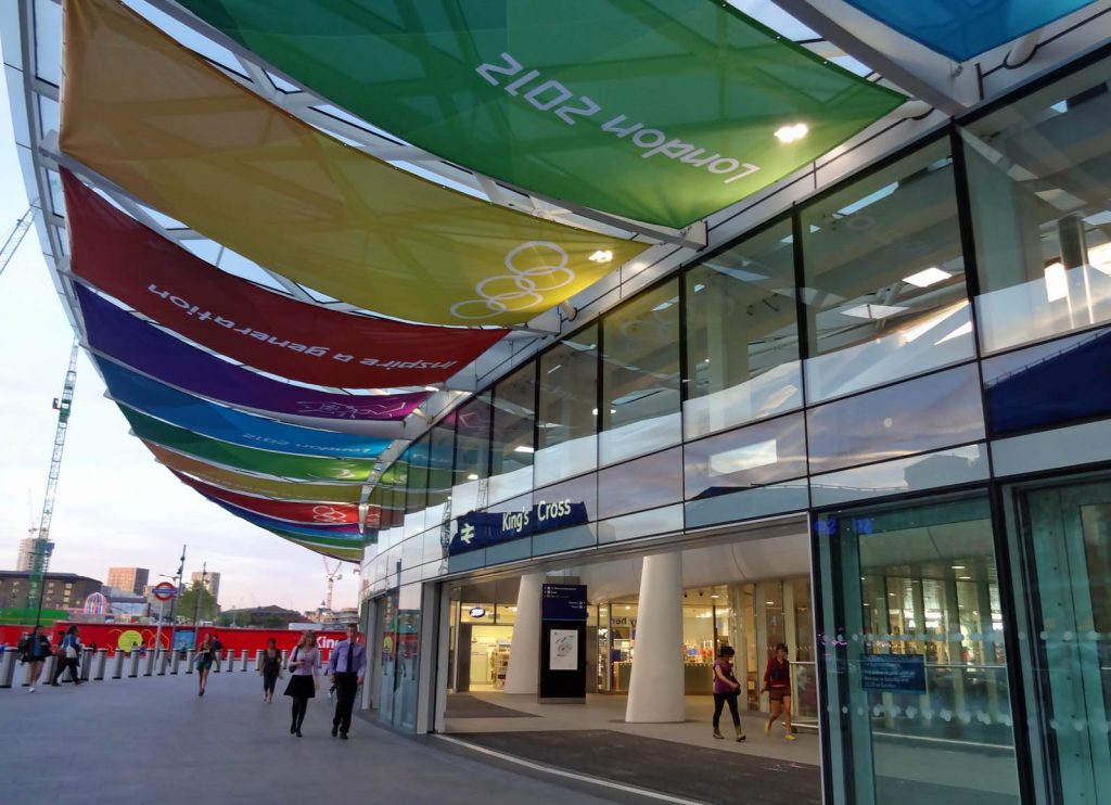 The outside of the new King's Cross station concourse, decorated with coloured banners with London 2012 logos and slogans