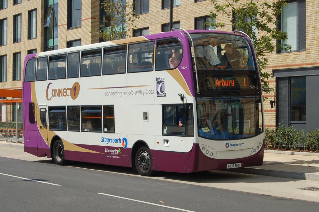 Photo of a double-decker bus. The destination blind says it is on a route 1 service to Arbury. The bus belongs to Stagecoach and is liveried in predominantly white with purple, madder and gold areas, and is route-branded for Lincolnshire Connect route 1.