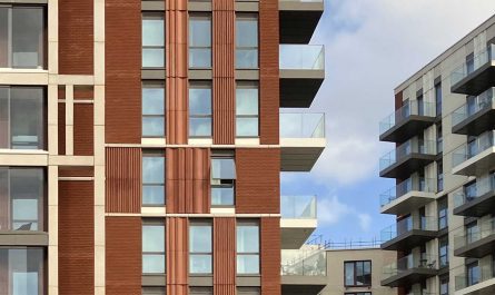 Photo of parts of some modern residential apartment buildings, on a sunny day. The flats all have balconies.