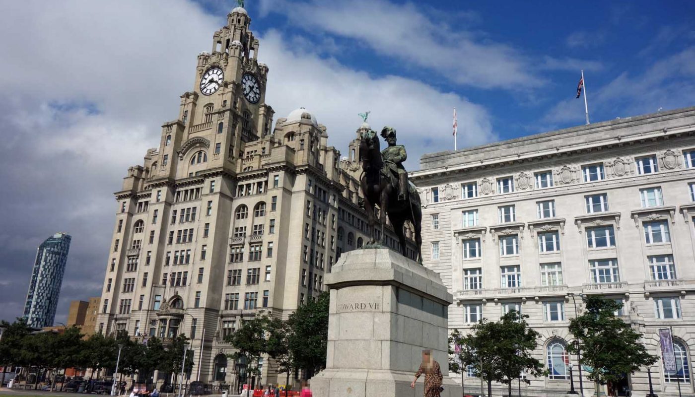 Photo of two of the 'Three Graces' in Liverpool, with the King Edward VII statue in the foreground and a modern tall building in the corner of the photo.