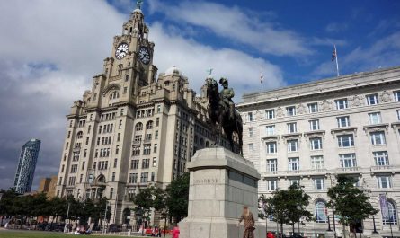 Photo of two of the 'Three Graces' in Liverpool, with the King Edward VII statue in the foreground and a modern tall building in the corner of the photo.