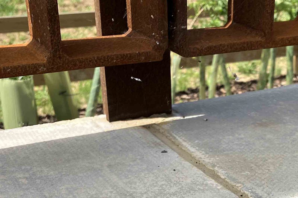 Detail photo of the base of the railings at the back of the side platforms, showing that the coping stones are cut to accept the stanchions.
