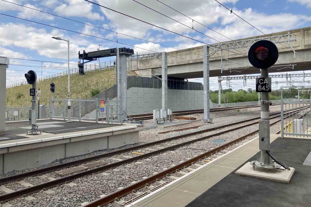 Phto at the north end of the platforms at Cambridge south station. Nearest the camera are fixed red LED colour-light signals CA845 and CA843. Beyond are the multiple aspect signals for the down platforms. Beyond them is an overbridge.